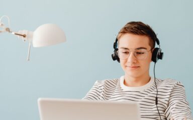 Student wearing a black pair of headphones while using his laptop